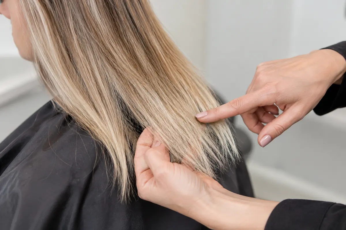 Stylist discussing the ends of a lightened hair section