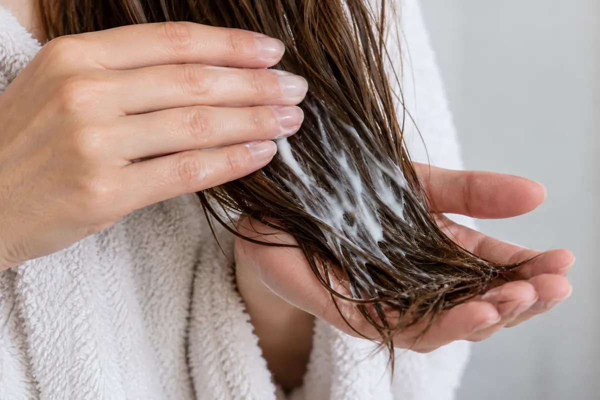 Hands smoothing conditioner over the lower hair lengths