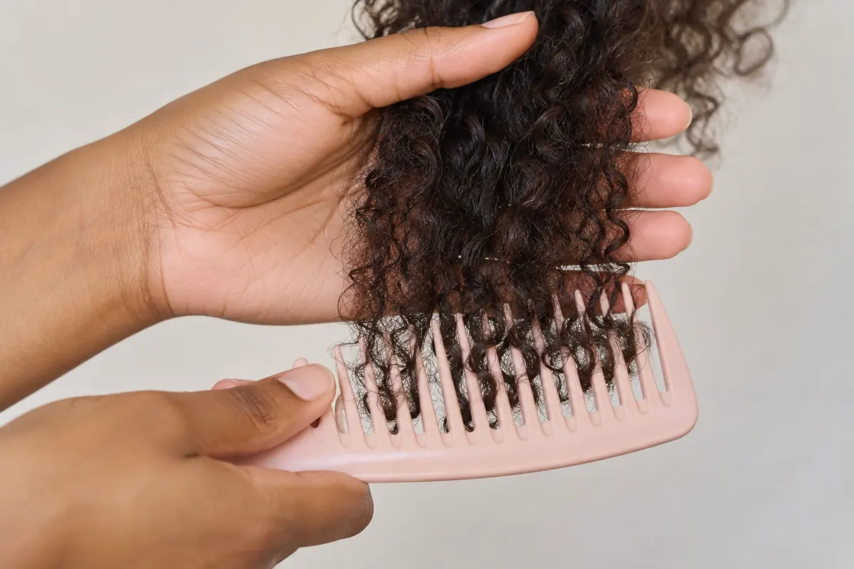 Hands gently detangling the ends of a small hair section
